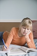 Girl doing homework on bed. Date : 2008