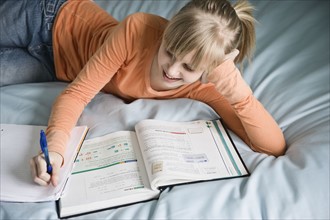 Girl doing homework on bed. Date : 2008