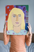 Girl holding painting in front of face. Date : 2008