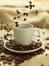 Coffee beans raining down on mug. Date : 2008