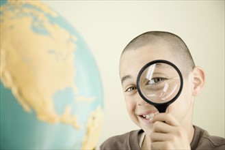 Boy looking through magnifying glass. Date : 2008