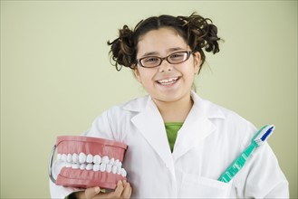 Girl holding model of teeth and toothbrush. Date : 2008