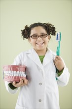 Girl holding model of teeth and toothbrush. Date : 2008