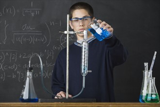 Boy pouring liquid in science class. Date : 2008