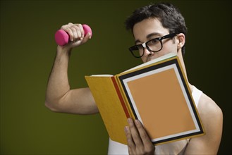 Nerdy man lifting weight and reading book. Date : 2008