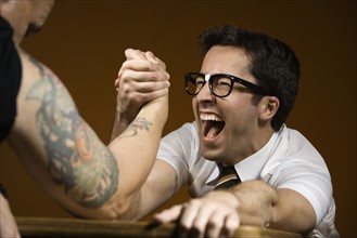 Nerdy man arm wrestling tattooed man. Date : 2008