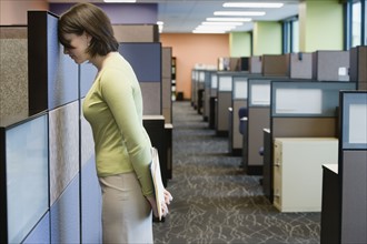 Businesswoman leaning head on cubicle wall. Date : 2008