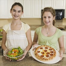 Teenaged girls holding salad and pizza. Date : 2008