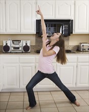 Teenaged girl singing in kitchen