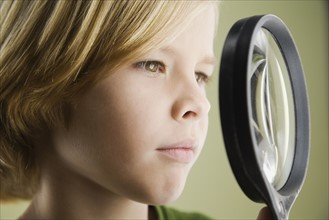 Boy looking through magnifying glass. Date : 2008