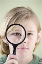 Boy looking though magnifying glass. Date : 2008