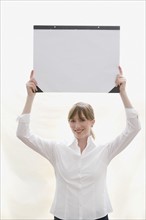 Woman holding desk blotter over head. Date : 2008