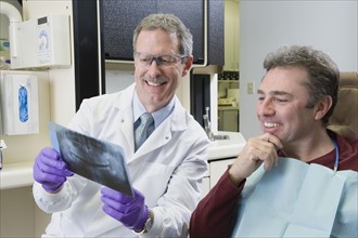 Male dentist and patient looking at x-ray. Date : 2008