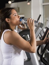 Woman drinking water on exercise machine. Date : 2008