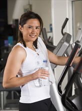 Woman holding water bottle on exercise machine. Date : 2008