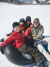 Family sitting on tube in snow. Date : 2008
