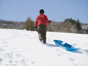 Boy pulling sled in snow. Date : 2008
