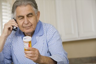 Senior man reading medication bottle. Date : 2008
