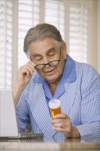 Senior man reading medication bottle. Date : 2008