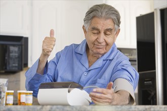 Senior man taking own blood pressure. Date : 2008