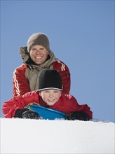 Father and son on sled in snow. Date : 2008