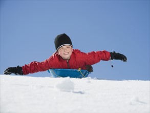 Boy laying on sled in snow. Date : 2008