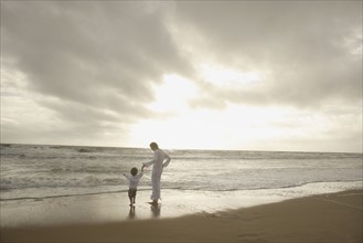 Mother and child holding hands at beach. Date : 2008