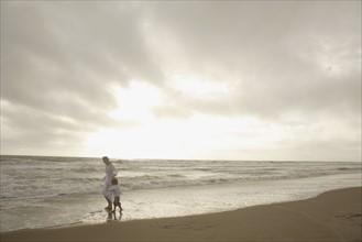 Mother and child walking on beach. Date : 2008