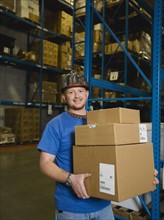 Warehouse worker holding stack of boxes. Date : 2008