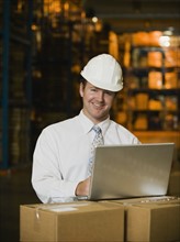 Businessman wearing hard hat in warehouse. Date : 2008