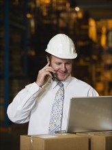 Businessman talking on cell phone in warehouse. Date : 2008