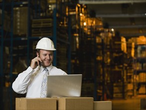 Businessman talking on cell phone in warehouse. Date : 2008
