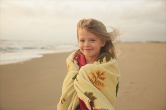 Girl wrapped in blanket at beach. Date : 2008