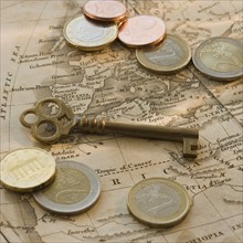 Close up of euro coins, map and antique key.