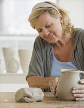 Senior woman making ceramic pot.