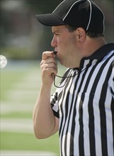 Football referee blowing whistle.