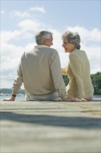 Senior couple sitting on dock.