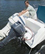 Man adjusting engines on speed boat.