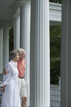 Senior couple standing on front porch.