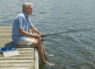 Senior man fishing off dock.
