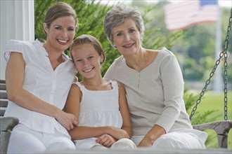 Three generations of women sitting on porch.
