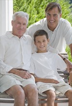 Three generations of men posing on porch.
