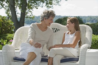 Grandmother and granddaughter sitting on porch.