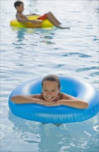 Children playing with inflatable tubes in swimming pool.