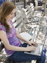 Woman using laptop on park bench. Date : 2008