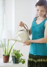 Teenage girl watering houseplant. Date : 2008