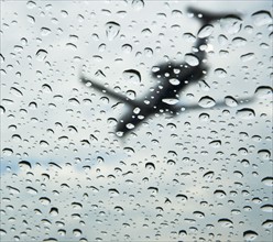 Low angle view of airplane through rain drops on window. Date : 2008