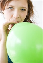 Teenage girl blowing up balloon. Date : 2008