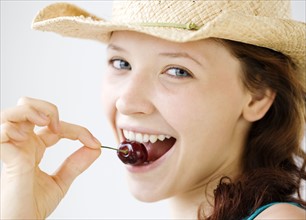Teenage girl in cowboy hat eating cherry. Date : 2008