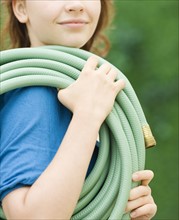 Teenage girl carrying garden hose. Date : 2008